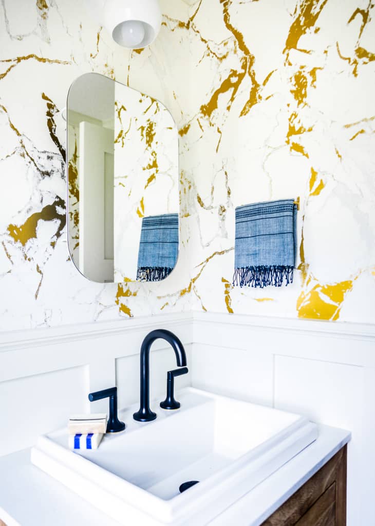 Half bathroom with marble wallpaper and frameless mirror