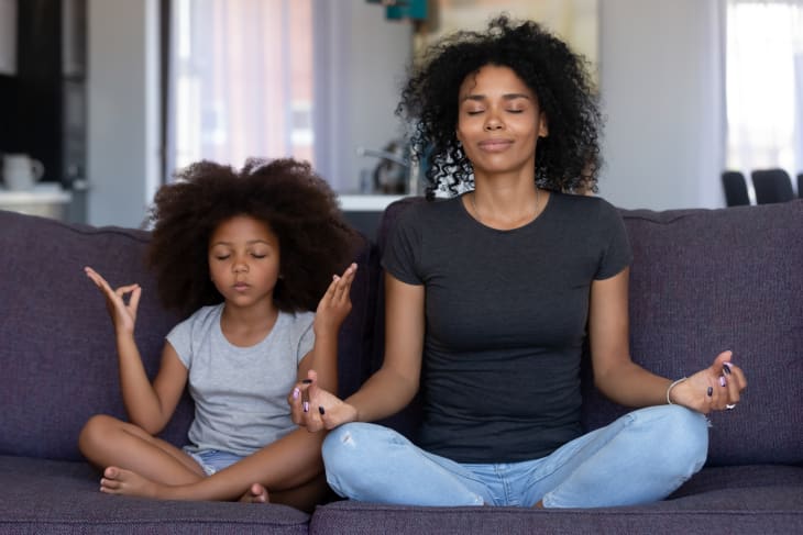 Mindful mom with cute kid daughter doing yoga exercise at home