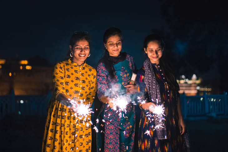 Three young Indian women with bengal fireworks, celebrating Indian Festival Diwali.