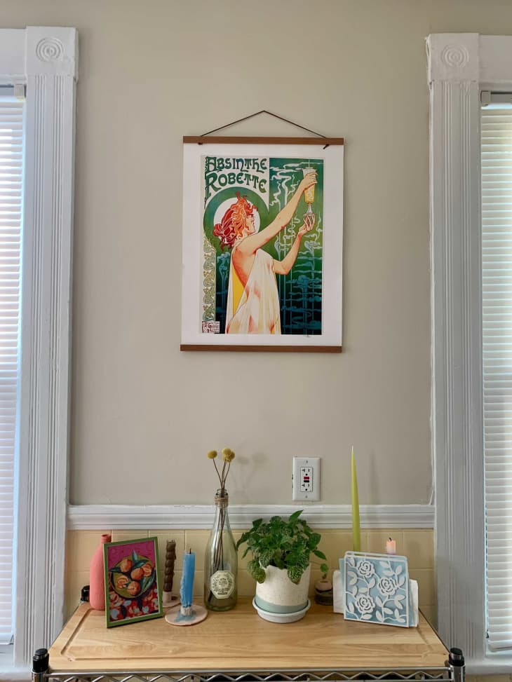 Art print hanging on wall above butcher block with candles and plant