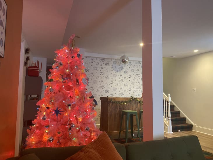 Basement with pink Christmas tree covered in lights and ornaments