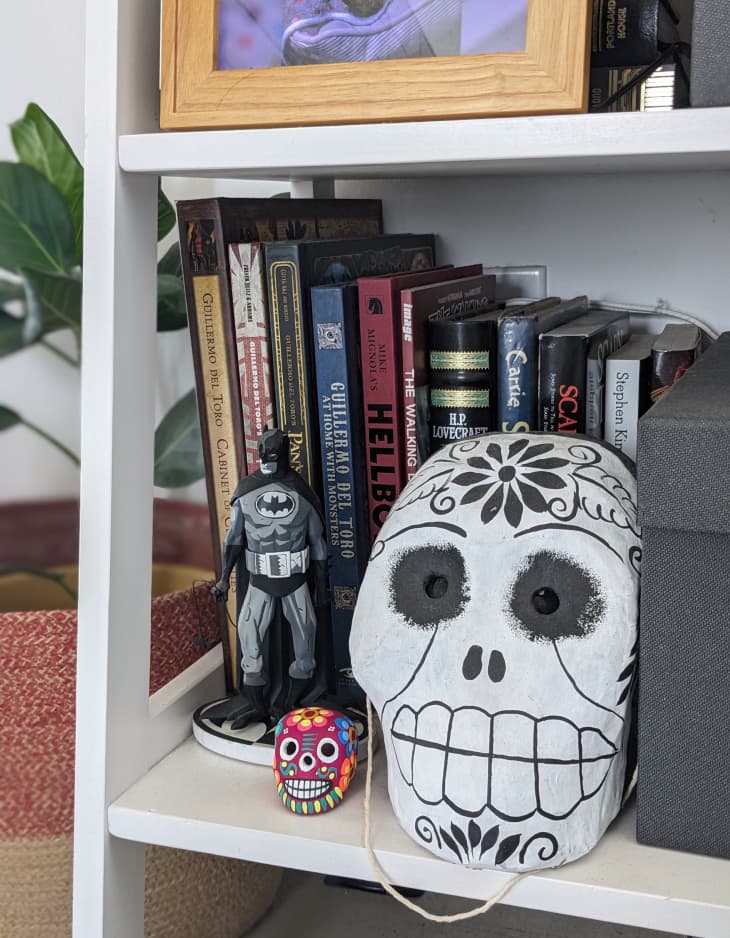 White bookcase with books, action figures and skulls.
