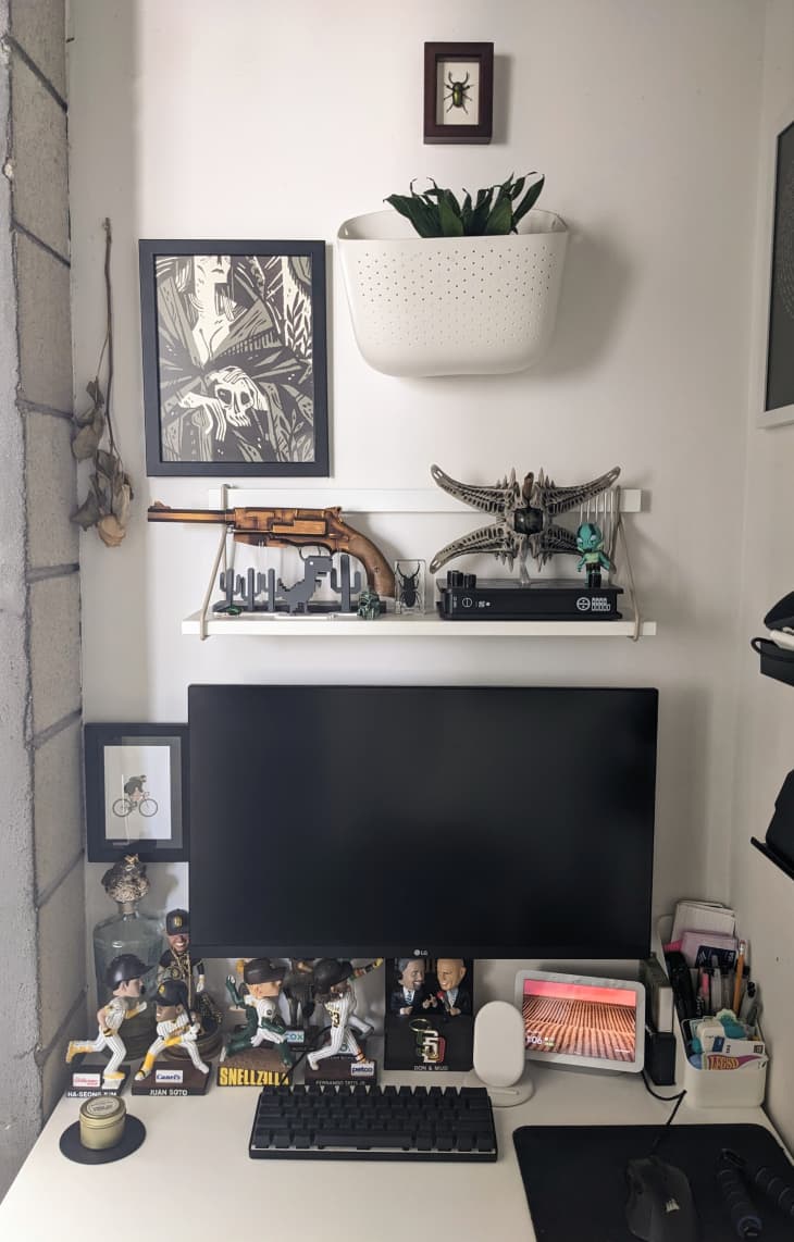 Monitor on desk with bobble heads in a white room.