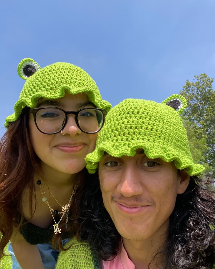 2 people wearing crocheted frog hats
