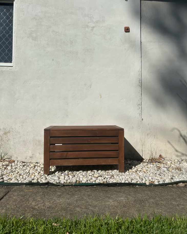 Wooden IKEA storage bench outside of building.