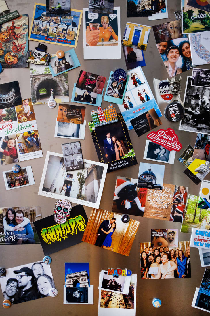 Close up front of a refrigerator door with magnets, photos, and other trinkets cluttering the front
