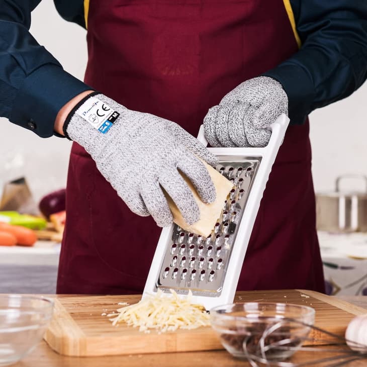 Grating cheese in the kitchen wearing cut-proof gloves