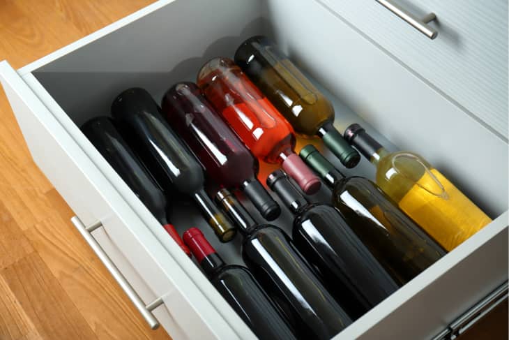 Open kitchen drawer with assortment of wine bottles inside