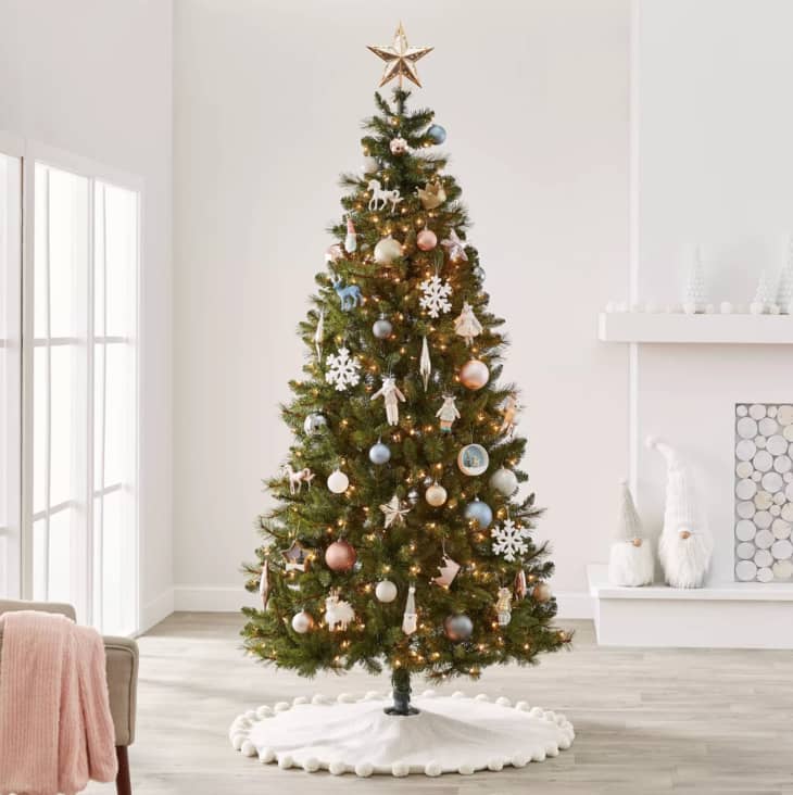 Christmas tree with gold star, pastel-colored ornaments, and white puff ball skirt