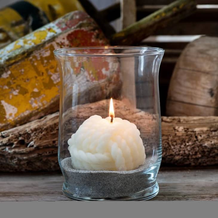 White beeswax candle shaped like knotted rope in glass jar