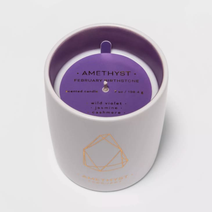 Violet-scented candle in white vessel