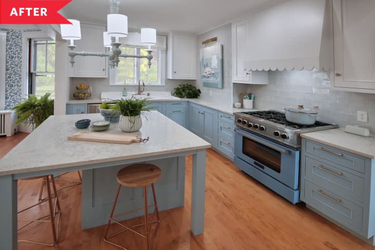After: Large, open kitchen with big island, gas range, and pale blue lower cabinets