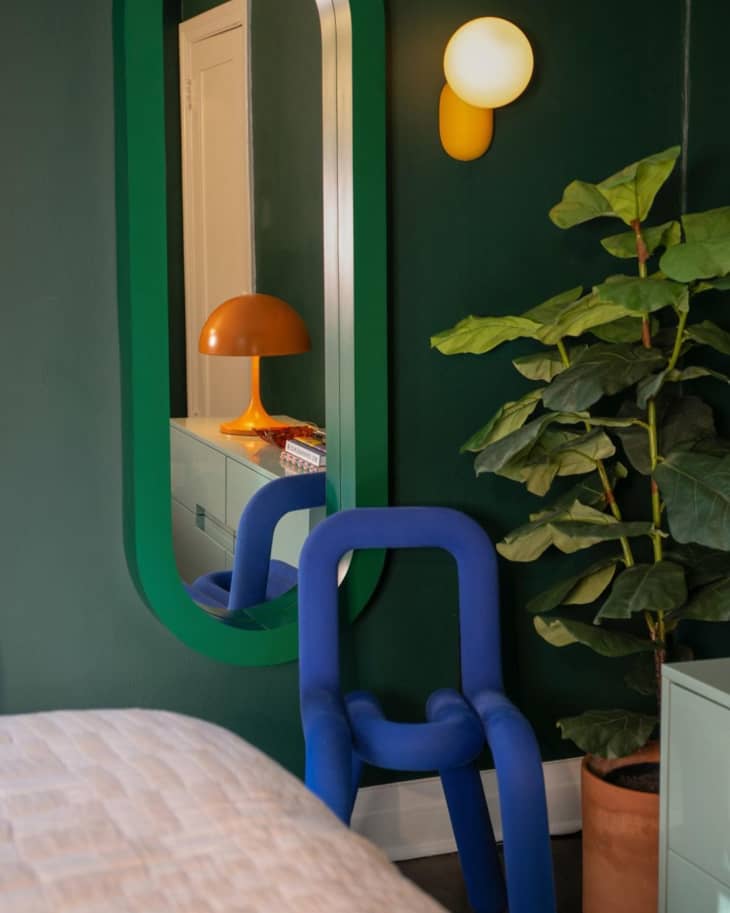 Green wall and mirror next to blue art deco chair