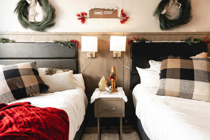 Two beds with plaid pillows and wreaths over the bed
