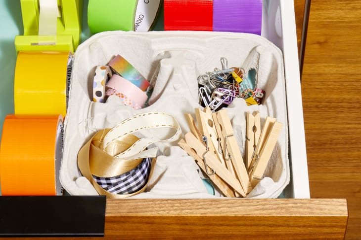 Close up shot of a cardboard drink holder being used to organize miscellaneous craft supplies inside of a drawer.