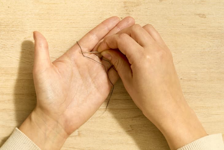 Shot of two hands threading a needle using the "magic" method.