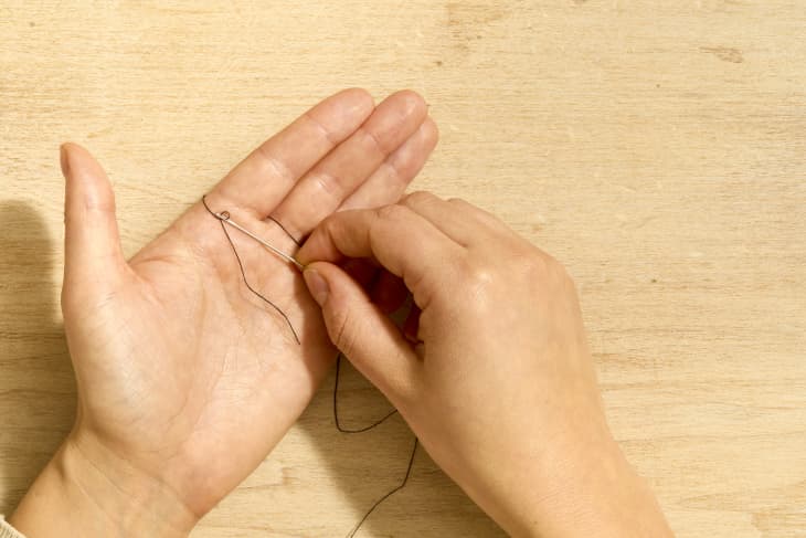 Shot of two hands threading a needle using the "magic" method.