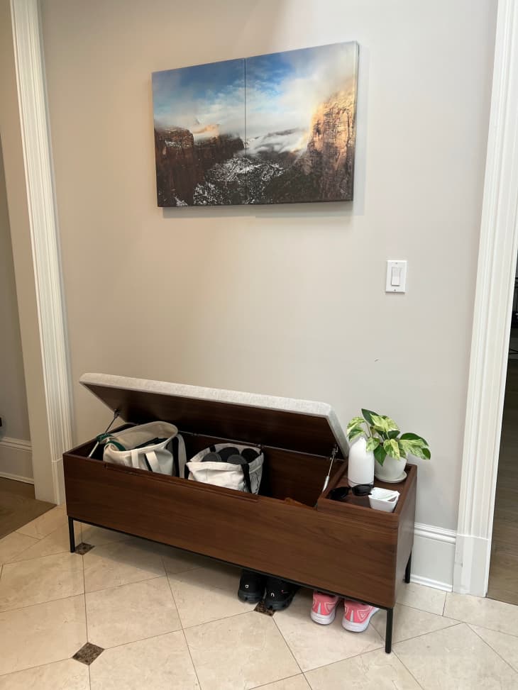 storage bench with liftable seat in hallway below artwork