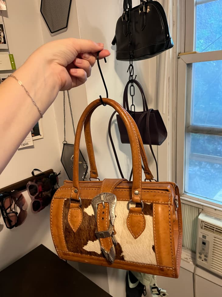 Someone holding purse on hook.