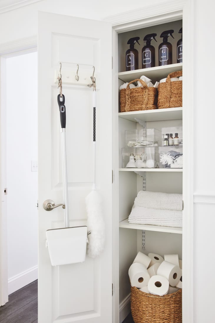hall closet with baskets of toilet paper, towels, cleaning supplies