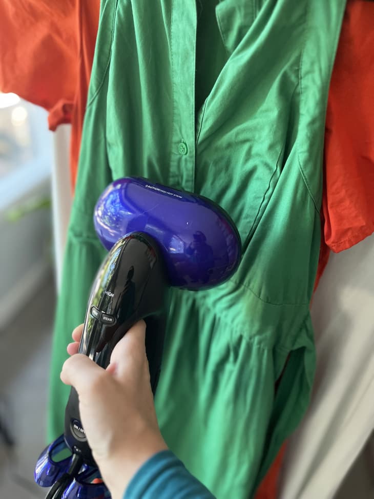 Photo of someone using a fabric steamer to get wrinkles out of clothes