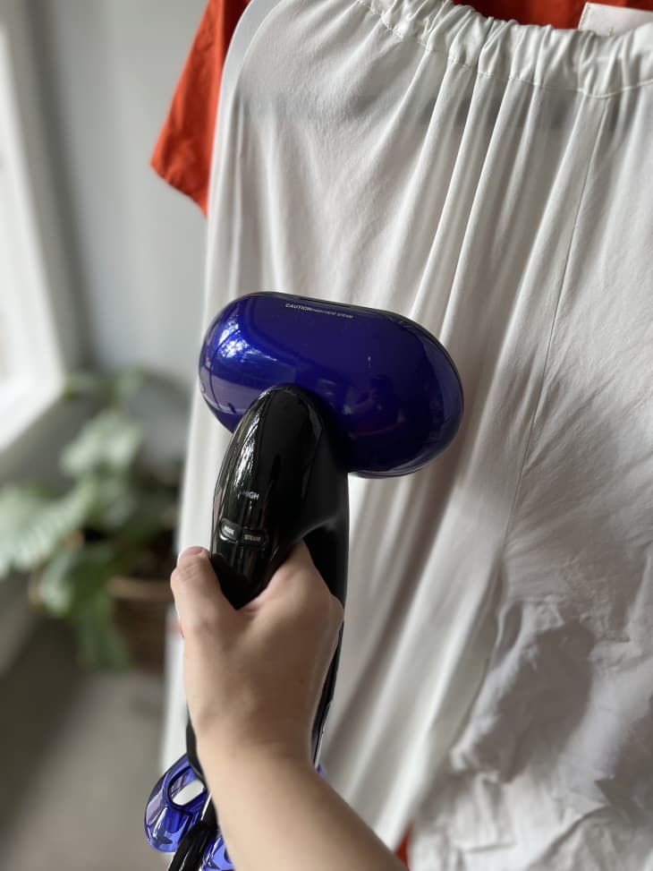 Photo of someone using a fabric steamer to get wrinkles out of clothes