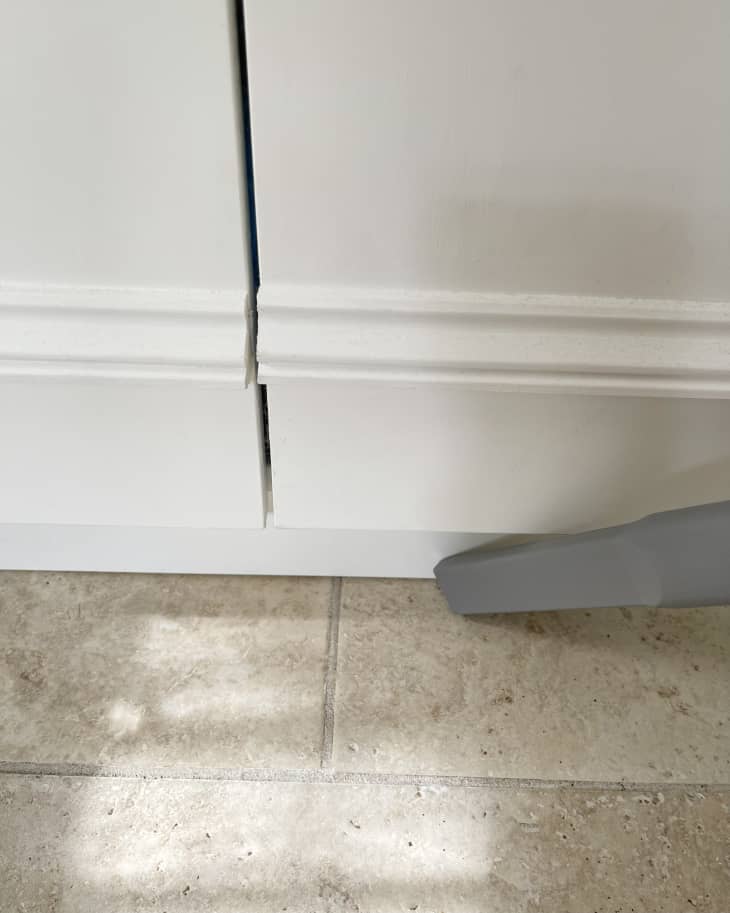 Someone using vacuum attachment to clean tile floors.