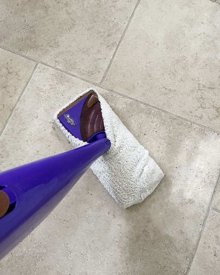 Someone using Swiffer to clean tile flooring.