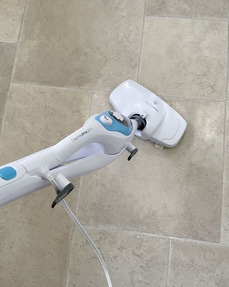 Someone using steam cleaner to mop tile floors.