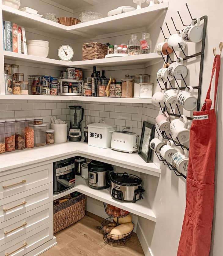 build in counter with some lower cabinets, floating shelves on the corner and short wall, white subway tile, mug rack for hanging mugs and hook for apron