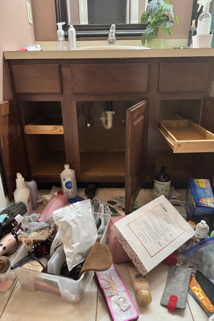 under sink cabinets emptied out with bathroom products scattered on the floor