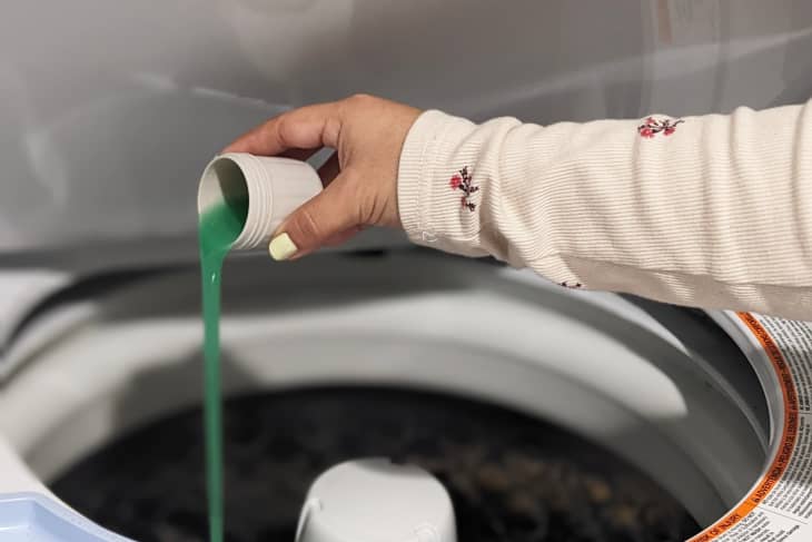 Washer drum with green laundry detergent being poured in