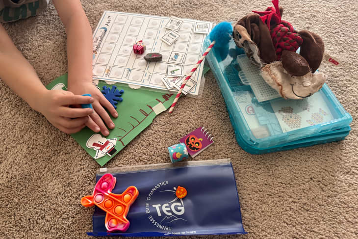 Toys, papers, and pencil case laid out on beige carpet