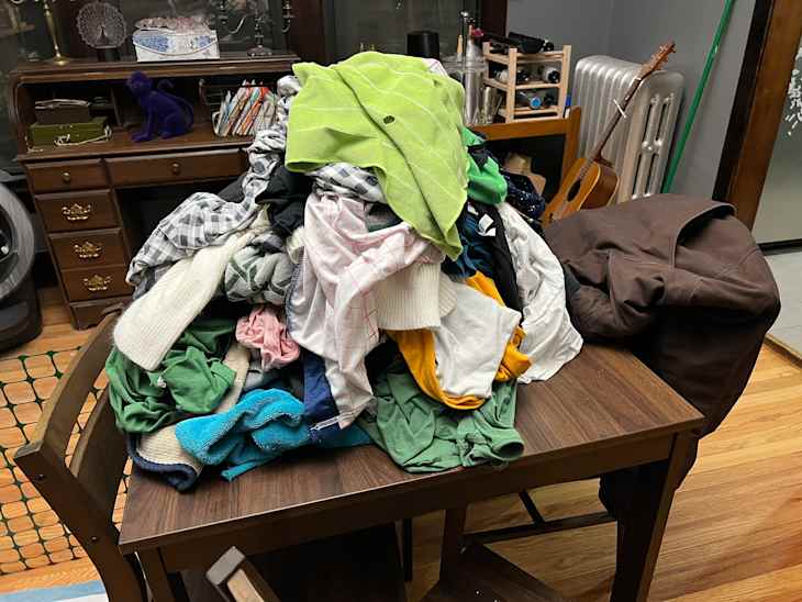 Pile of clothes on dining table.