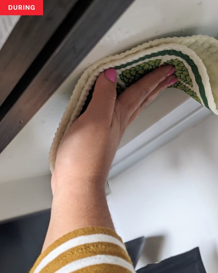 Someone using dishcloth to clean kitchen cabinet using TikTok cleaning hack.