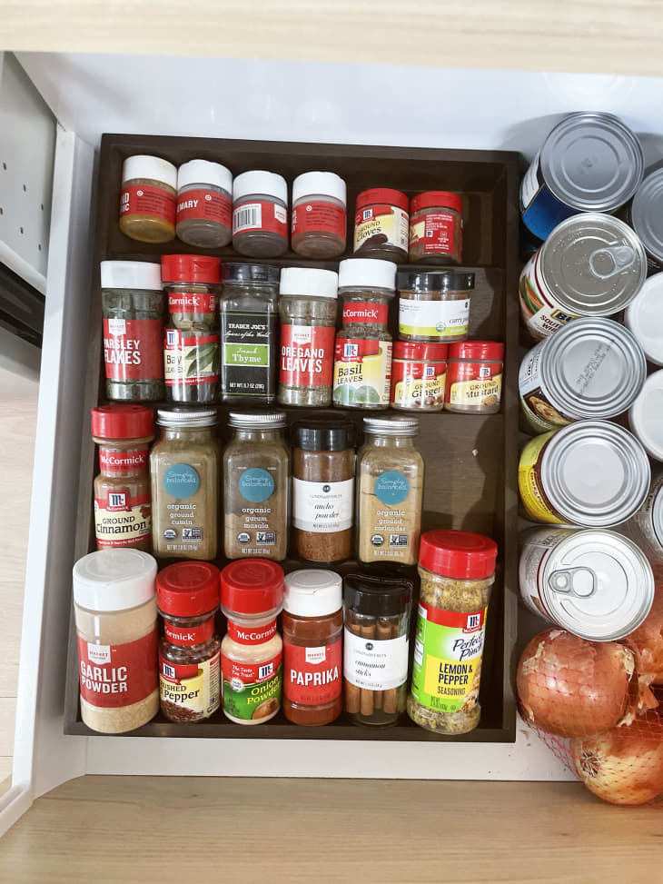 A spice organizer filled with jars of spices inside a kitchen drawer
