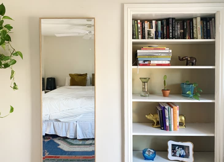 A full-length bedroom mirror and organized built-in bookshelves