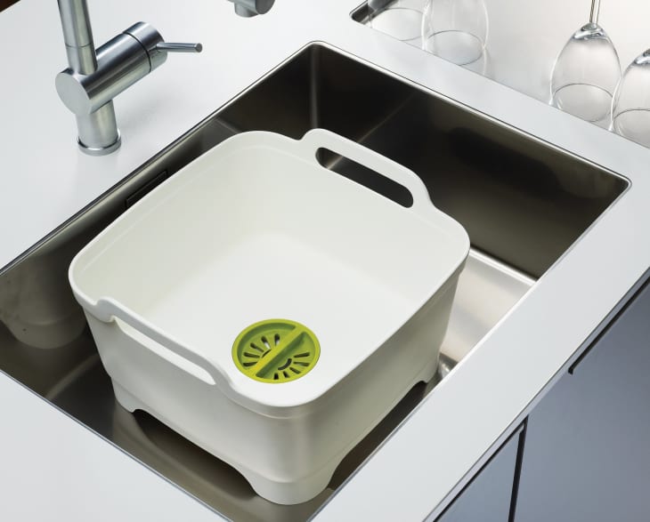 A white plastic wash tub inside a modern sink