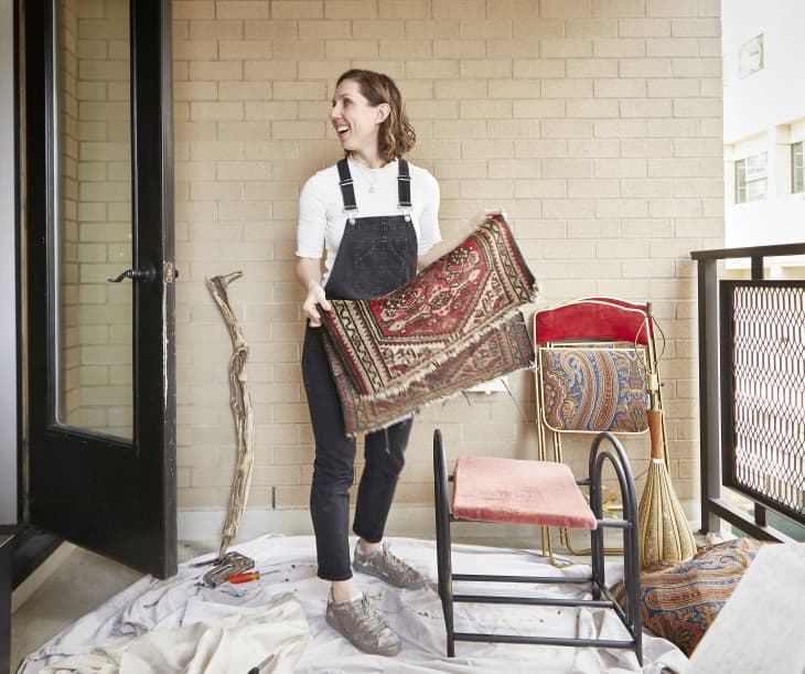 Bronwyn Tarboton in her refurbishing workspace on her deck, holding a rug