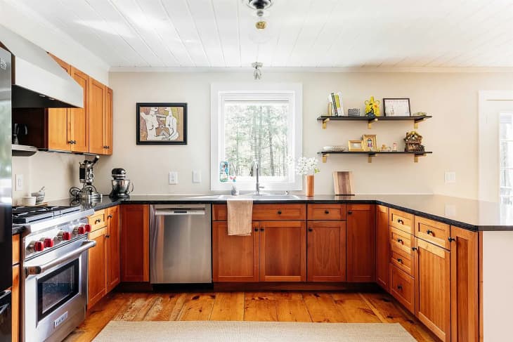 Light filled kitchen with wooden cabinets and gas range in historic home.