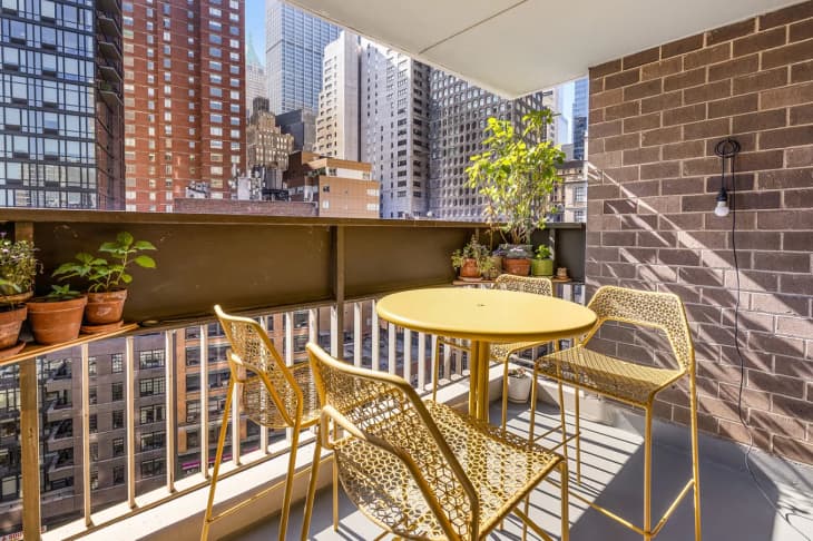 Yellow patio furniture on a patio with plants and a view of New York.