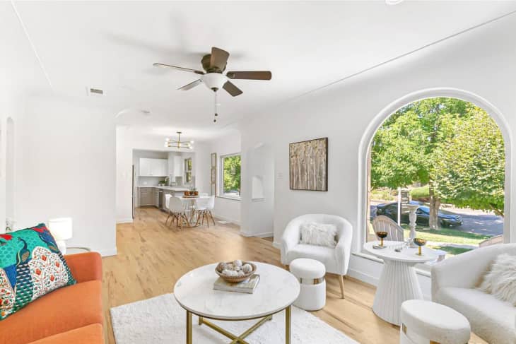 white living room with large arched window and wood floors