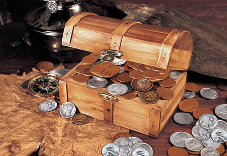 Small wooden chest filled with and surrounded by coins