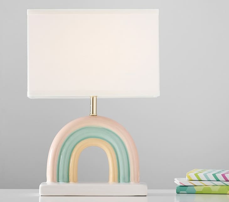 Table lamp with a rectangular linen shade and a ceramic rainbow shaped base.