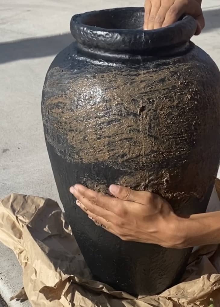 Making a mud vase with a black spray painted vase and a dirt-water mixture