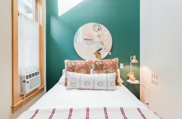 Small bedroom with bold green wall designed by The Sursey