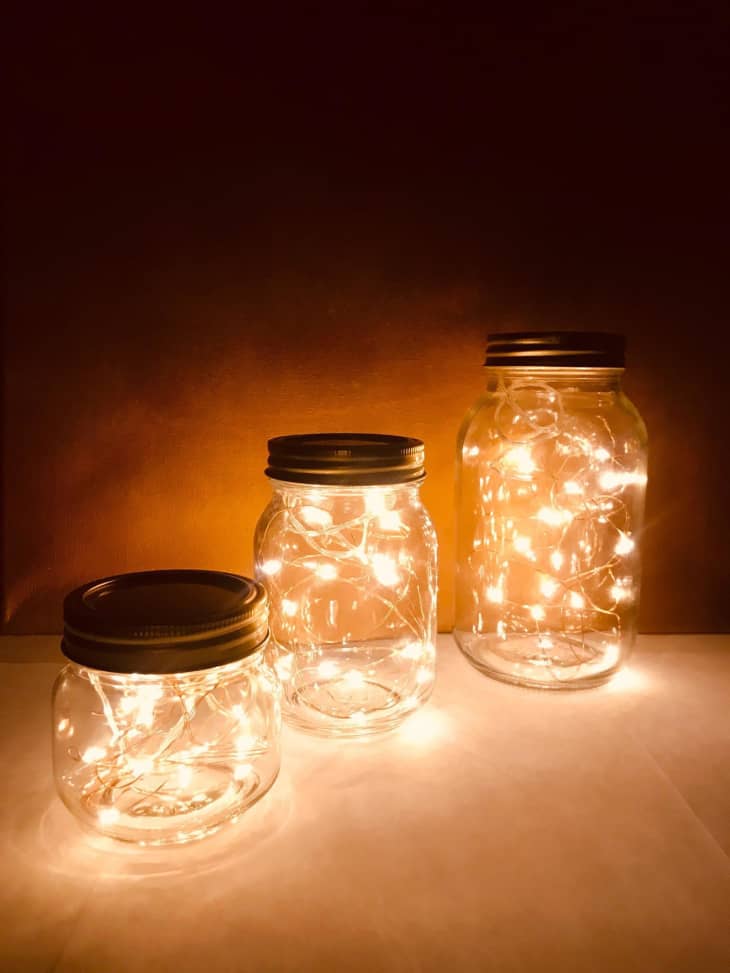 Three mason jars with fairy lights inside