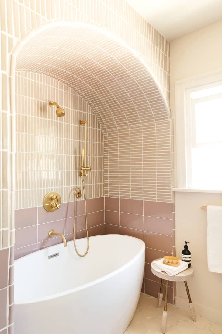 Tiled bathroom with an arch over the bathtub designed by Anne Sage