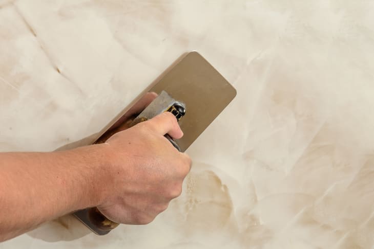 Hand applying a Venetian plaster treatment to a wall