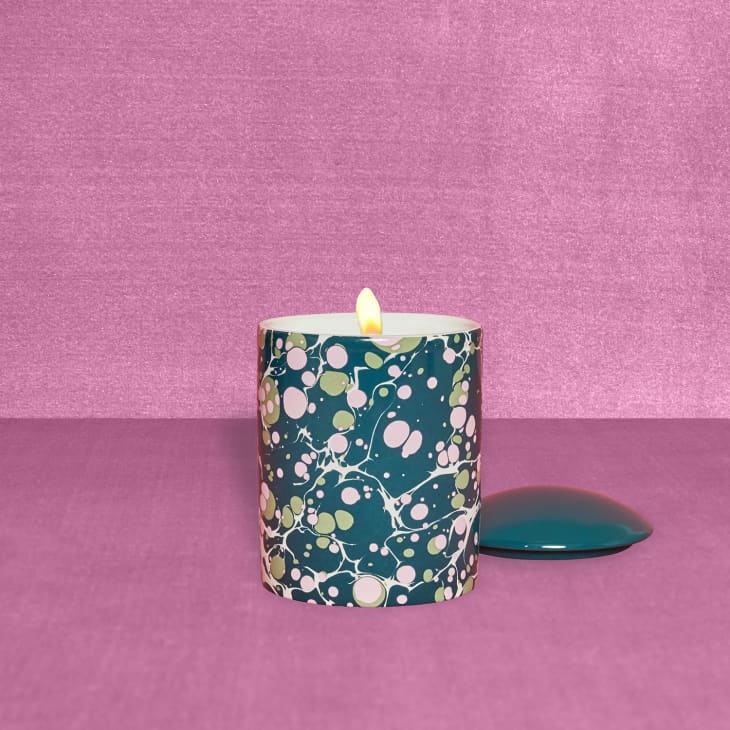 A floral candle on a pink backdrop